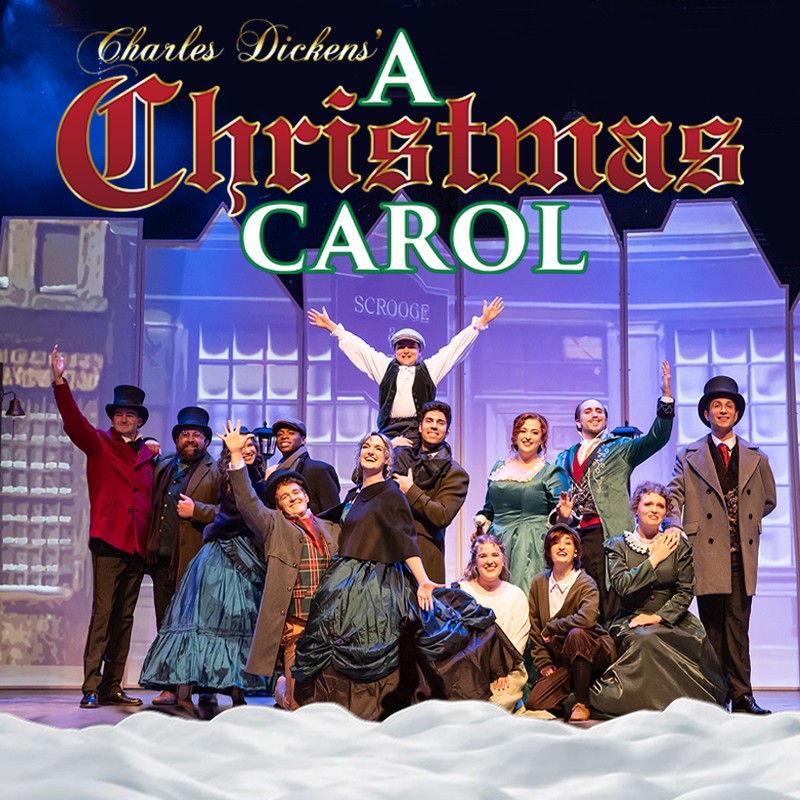 Group of theatre performers in Victorian costumes on stage for A Christmas Carol, with snowy foreground.